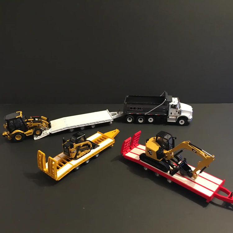 Collection of toy construction vehicles and transport trailers.